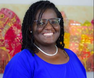 Tomyra Beverly wearing glasses with blue dress and white necklace