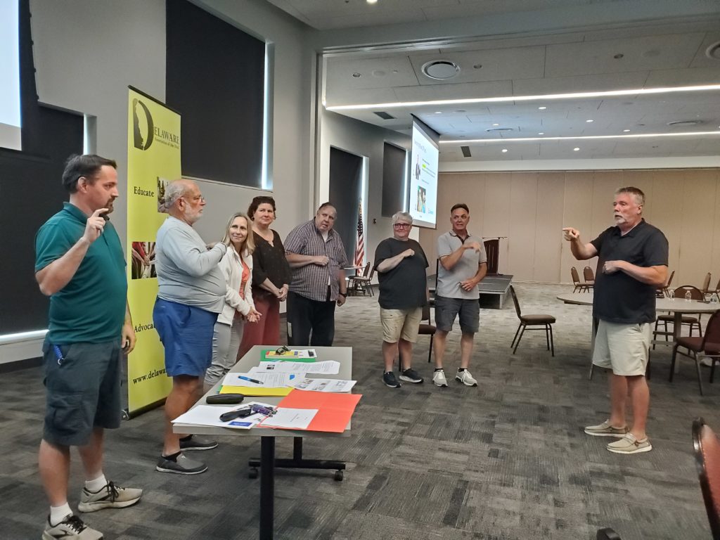 Elected officers take oath. Left to right: Feta Fernsler, green shirt, Gordon Bergan, Karen Miller, Judy McGuigan, George Delinois, Suz Dennis, Joey DeLusant and Billy Bowman in black shirt giving the oaths to all.