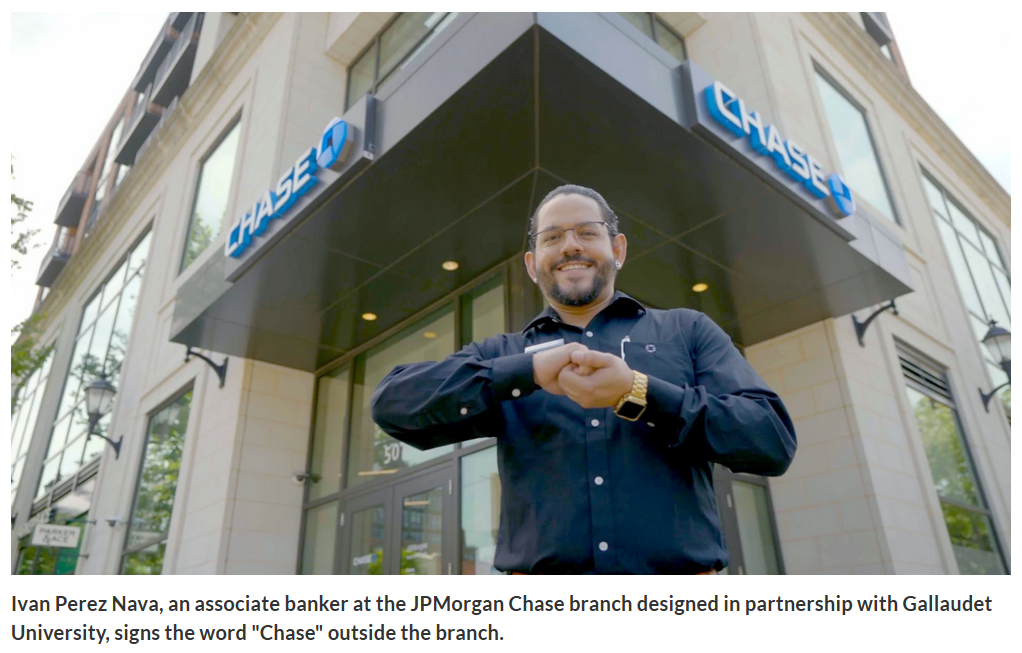 Ivan Perez Nava, associate banker at JPMorgan Chase branch near Gallaudet.  Ivan wearing a dark blue shirt with gold watch and glasses is signing 'chase' although it looks more like partnership.  Image from American Banker.