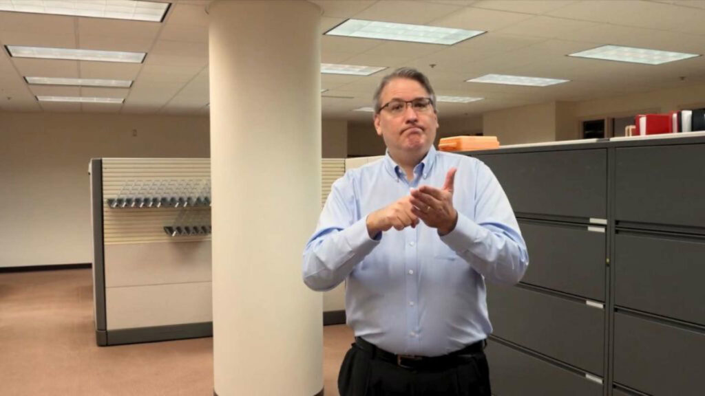 Robert Cooper signing in an office © Provided by The Wichita Beacon