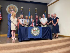 Governor Matt Meyer signs HB53 into law.  Red shirt is Eric Morrison, our main sponsor of the bill.  

Going left from Eric is Dave from DDSC, Feta Fernsler - President, Keith Robertson - VP and Elisha Jenkins - DOL/DVR.  