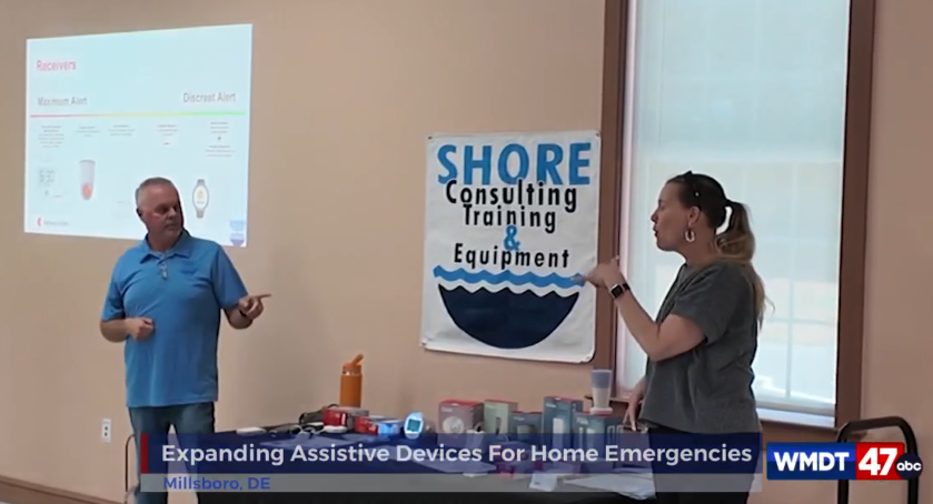 Michael Welter, on left side in blue shirt pointing at Christina Feil on right side in Greenish or Grey shirt. Table showcases a variety of Bellman devices from SHORE company.
